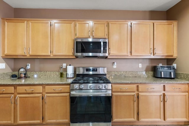 kitchen featuring light brown cabinets, light stone counters, and appliances with stainless steel finishes