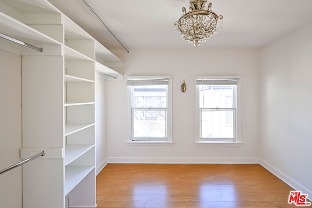 walk in closet featuring light hardwood / wood-style floors and a notable chandelier