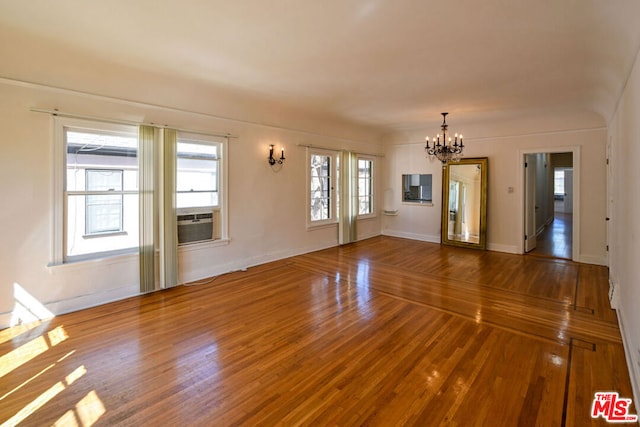 unfurnished room with hardwood / wood-style floors, cooling unit, a chandelier, and plenty of natural light