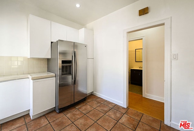 kitchen featuring white cabinetry, stainless steel fridge with ice dispenser, tasteful backsplash, and tile patterned flooring