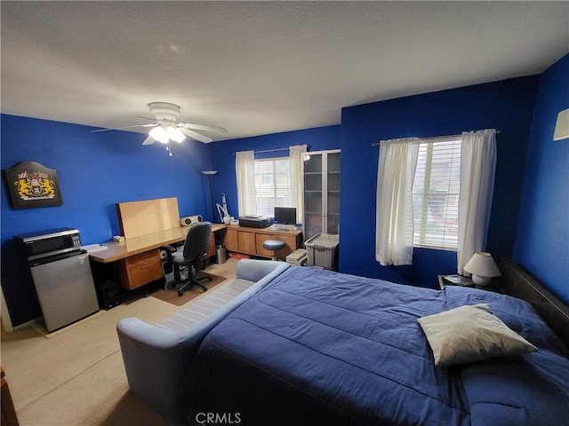 carpeted bedroom featuring ceiling fan and a textured ceiling