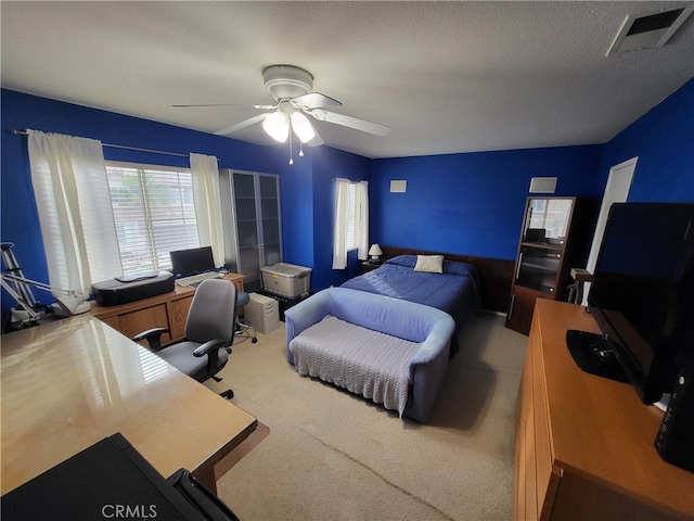 carpeted bedroom with ceiling fan and a textured ceiling