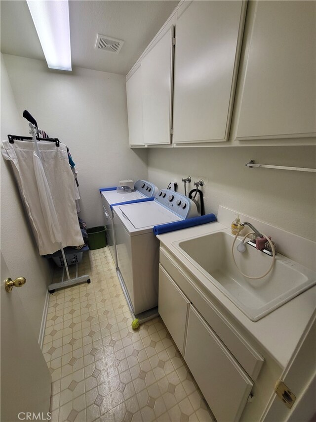 laundry area featuring cabinets, separate washer and dryer, and sink