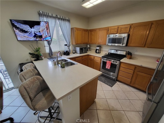 kitchen featuring a kitchen breakfast bar, sink, kitchen peninsula, and stainless steel appliances