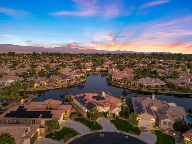 aerial view at dusk featuring a water and mountain view