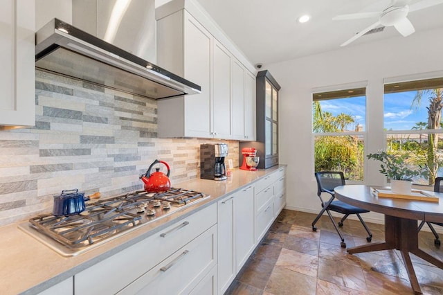 kitchen featuring white cabinets, backsplash, and wall chimney exhaust hood