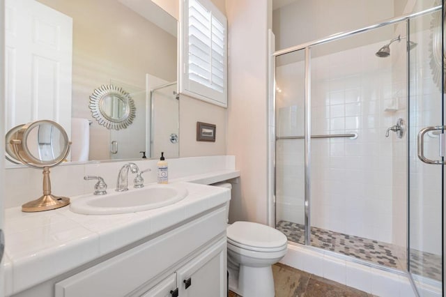 bathroom with vanity, a shower with shower door, and toilet