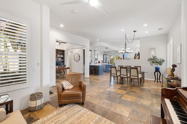 living room featuring ceiling fan with notable chandelier