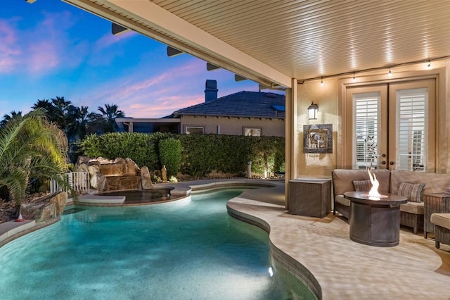 pool at dusk with a patio area and a fire pit