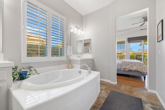 bathroom with vanity, tiled bath, and ceiling fan