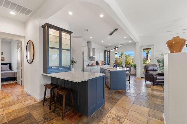 kitchen featuring a center island with sink, white cabinetry, a breakfast bar area, and kitchen peninsula