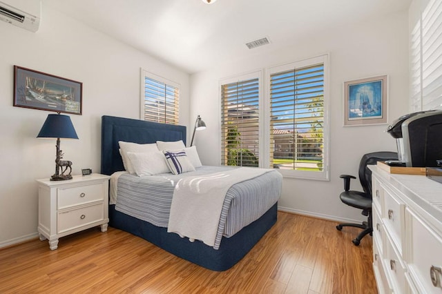 bedroom with a wall unit AC and light hardwood / wood-style floors