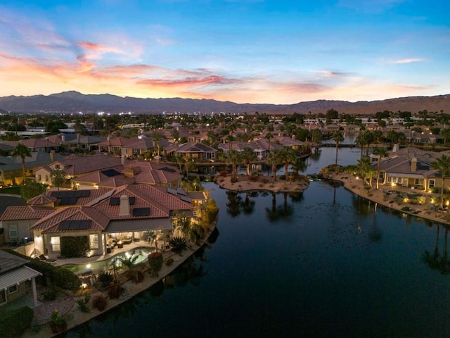 aerial view at dusk featuring a water and mountain view