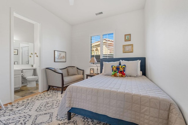 bedroom with ceiling fan, ensuite bath, and hardwood / wood-style floors