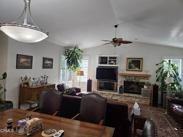 living room with a stone fireplace, ceiling fan, and lofted ceiling