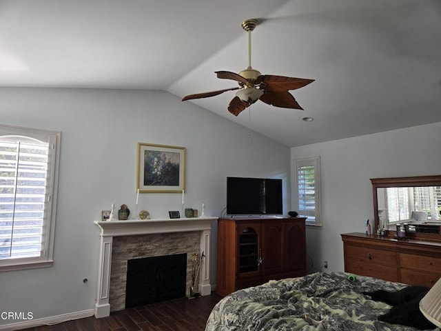 bedroom featuring a fireplace, ceiling fan, dark hardwood / wood-style flooring, and lofted ceiling