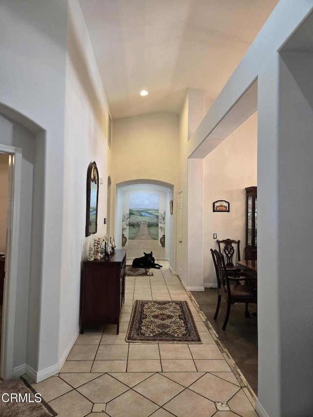 hallway featuring light tile patterned floors and high vaulted ceiling