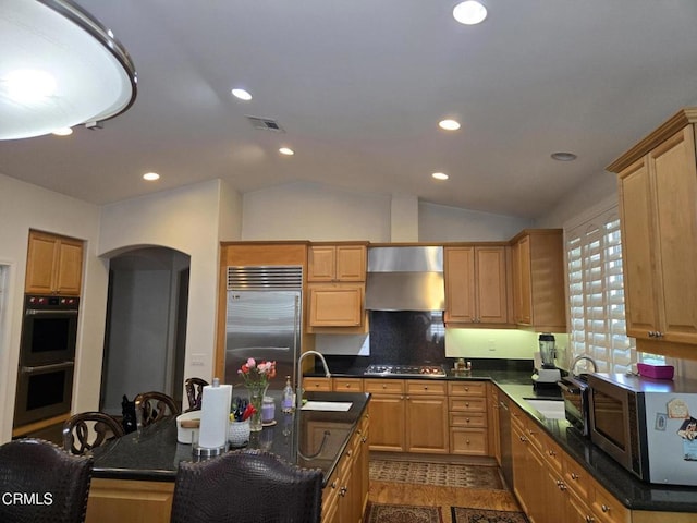 kitchen with appliances with stainless steel finishes, a breakfast bar, vaulted ceiling, sink, and a center island with sink