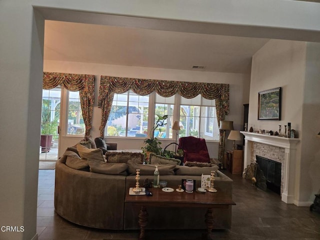 tiled living room with a stone fireplace