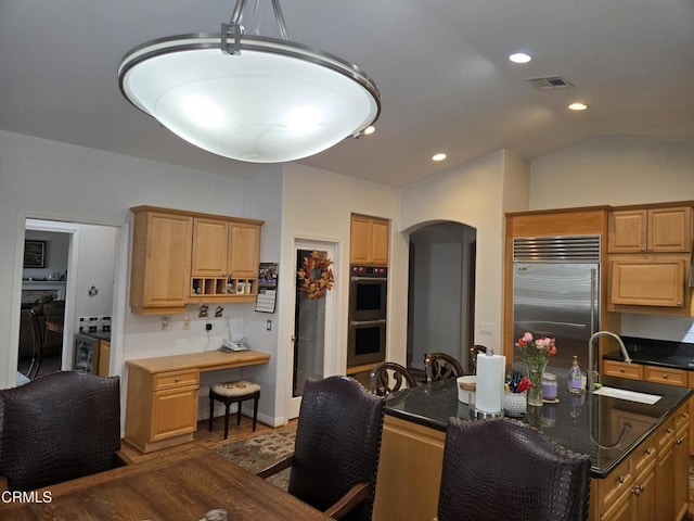 kitchen featuring pendant lighting, lofted ceiling, sink, and appliances with stainless steel finishes