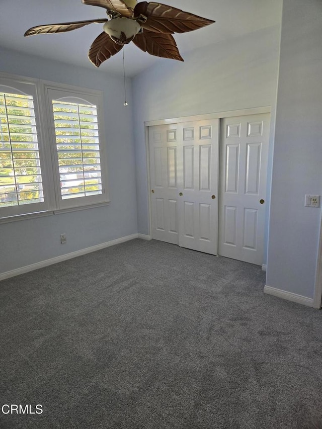 unfurnished bedroom featuring dark colored carpet, ceiling fan, and a closet