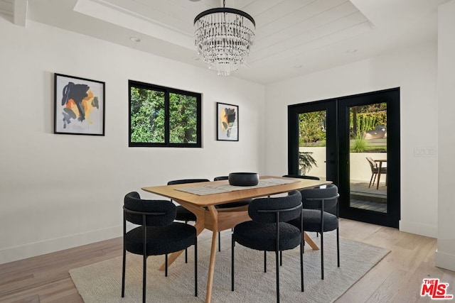 dining room with plenty of natural light, light hardwood / wood-style floors, french doors, and an inviting chandelier