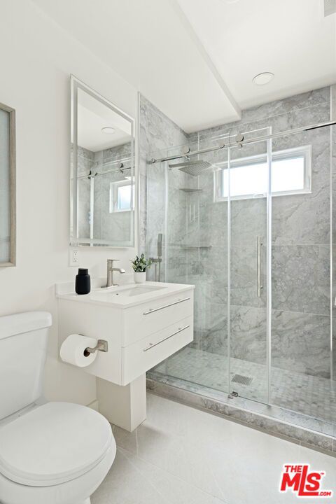 bathroom with tile patterned flooring, vanity, a shower with door, and toilet