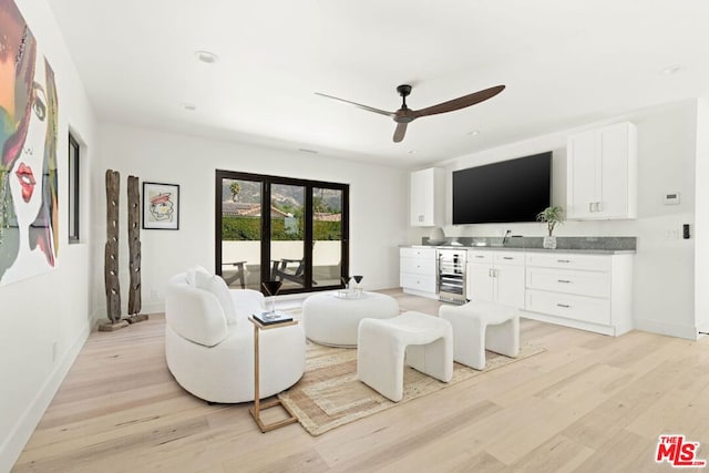 living room featuring ceiling fan, light wood-type flooring, and beverage cooler