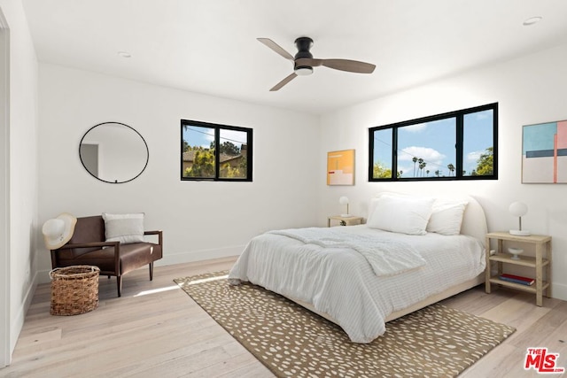 bedroom with multiple windows, ceiling fan, and light wood-type flooring