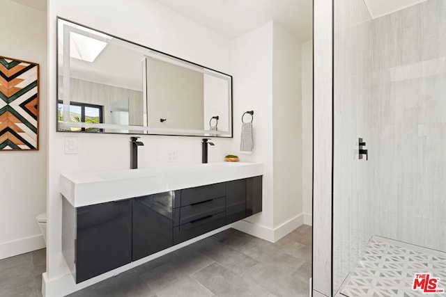 bathroom with a skylight, tile patterned floors, a tile shower, vanity, and toilet