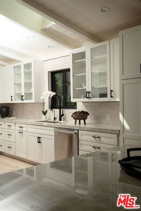 kitchen featuring stainless steel dishwasher, white cabinets, sink, and tasteful backsplash