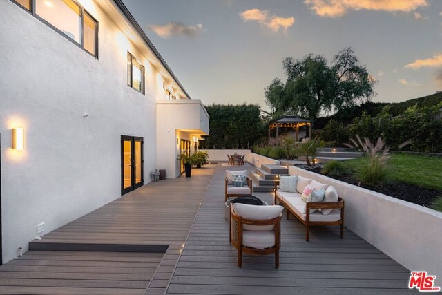 deck at dusk featuring a gazebo and an outdoor hangout area