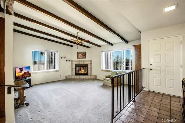 tiled living room with a tile fireplace, ceiling fan, and vaulted ceiling with beams