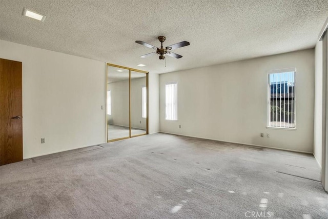 carpeted empty room featuring ceiling fan and a textured ceiling