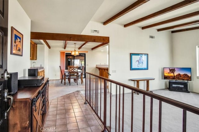 hall featuring tile patterned flooring, beam ceiling, and a notable chandelier