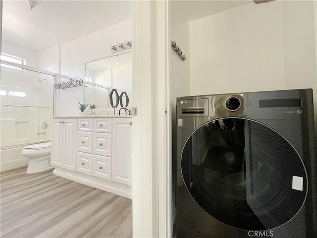 clothes washing area featuring light hardwood / wood-style floors and washer / dryer