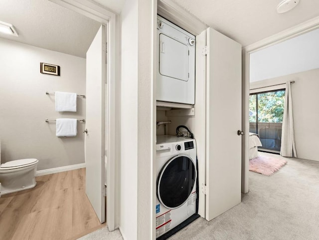 laundry room featuring light colored carpet and stacked washer / dryer