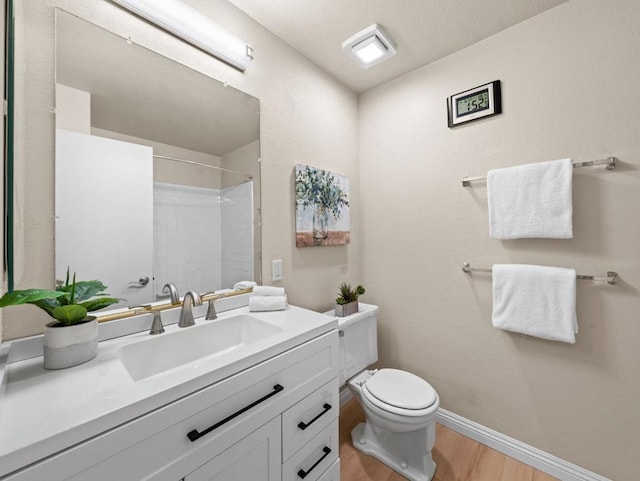 bathroom featuring hardwood / wood-style flooring, vanity, a shower, and toilet