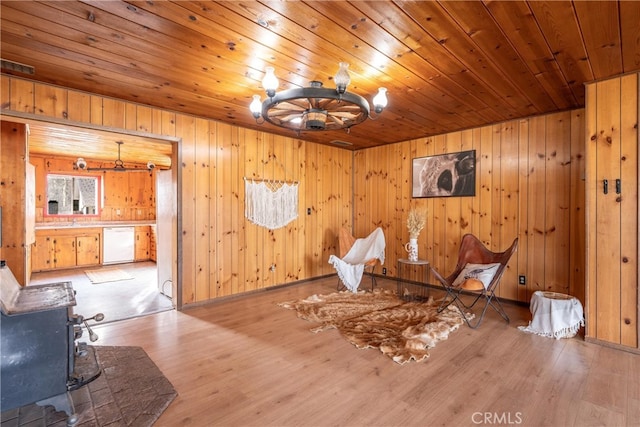 misc room featuring a wood stove, wood walls, light hardwood / wood-style floors, and wooden ceiling