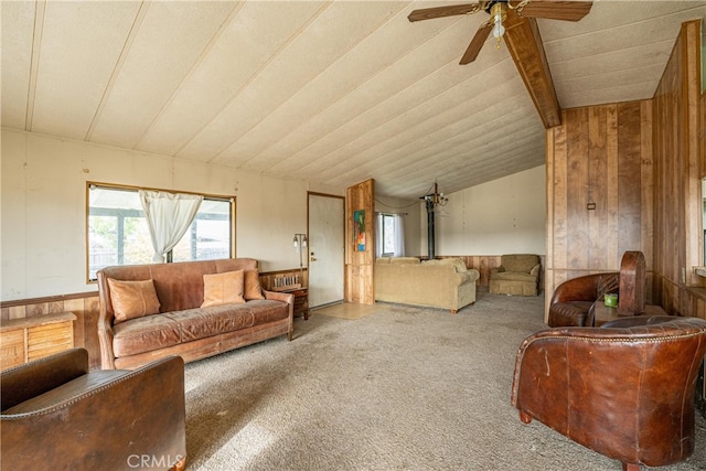 living room featuring ceiling fan, carpet floors, wooden walls, and vaulted ceiling