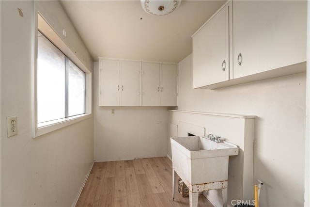 clothes washing area featuring light hardwood / wood-style flooring and sink