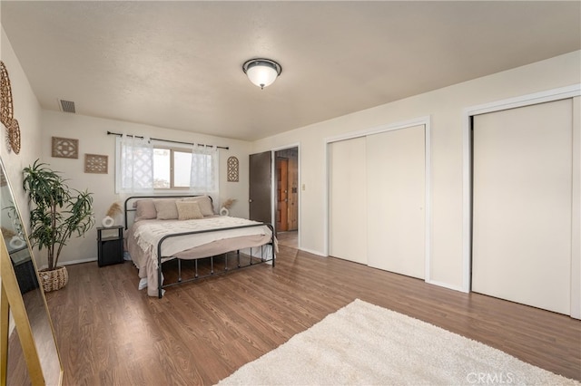 bedroom featuring dark hardwood / wood-style flooring and two closets