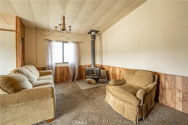 living room featuring carpet flooring, a wood stove, wood walls, and a textured ceiling