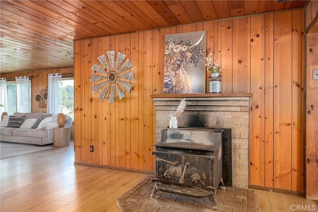 living room featuring a wood stove, light hardwood / wood-style flooring, wooden walls, and wood ceiling