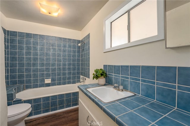 full bathroom featuring toilet, vanity, wood-type flooring, and tiled shower / bath