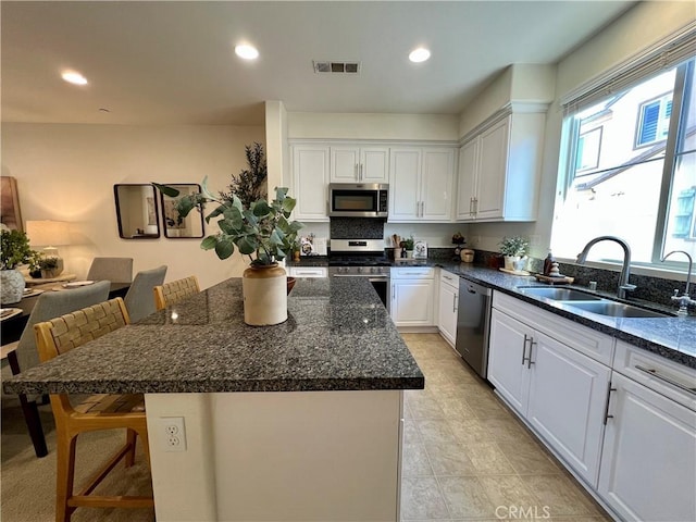 kitchen with sink, appliances with stainless steel finishes, a kitchen breakfast bar, and a kitchen island