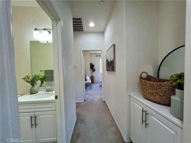 hallway featuring light carpet and sink