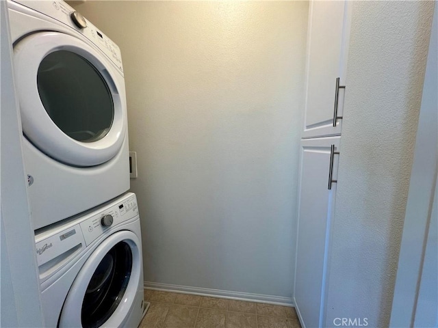 laundry room with cabinets, stacked washer / dryer, and light tile patterned floors