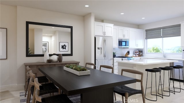 kitchen with a breakfast bar area, stainless steel appliances, a sink, white cabinetry, and a center island