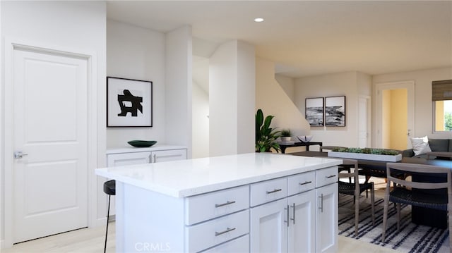 kitchen featuring open floor plan, a center island, light wood-style floors, white cabinetry, and recessed lighting